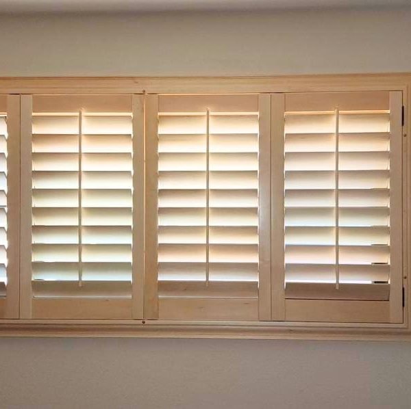 Elegant custom wooden shutters enhancing a cozy bedroom with warm tones and decorative wall art.
