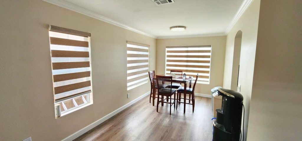 An inviting living room with a comfortable couch and a window with blinds and dual shades.