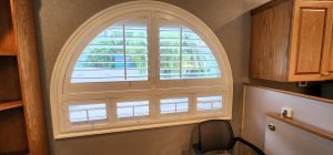 A well-lit room showcasing a window with decorative shutters adjacent to a functional desk, enhancing the ambiance.