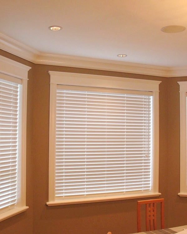 Dining room with elegant white horizontal blinds on bay windows, providing privacy and soft natural lighting.