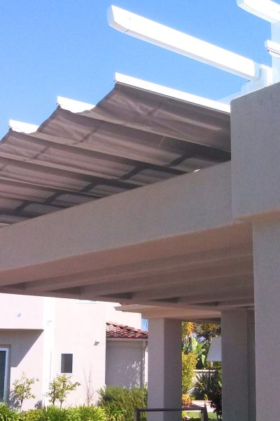 A spacious white pergola featuring awnings, elegantly integrated into the architecture of a house.