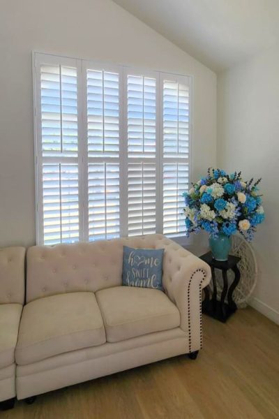 Elegant living room featuring white shutters and blue flowers, exuding a calming and stylish ambiance.